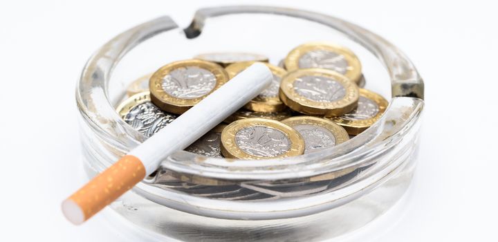 Cigarette and British Pound Coins in an Ashtray
