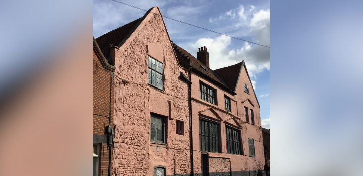 A pink stone building with a blue sky above it