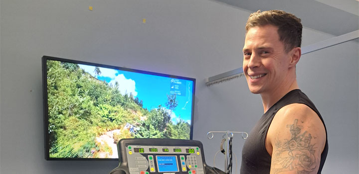 A man on a treadmill smiling at the camera