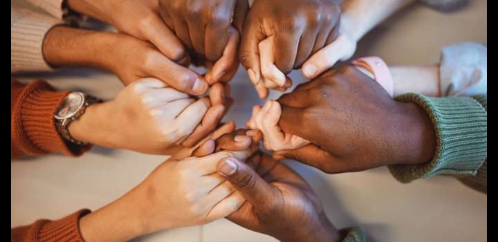 People's hands are holding each others' hands in a circle.
