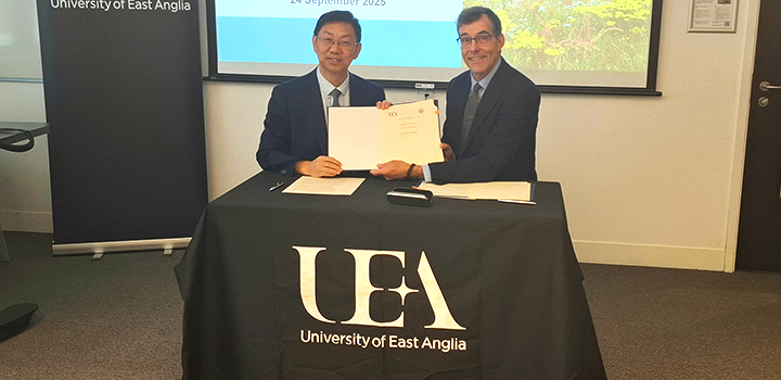 Two men sat behind a desk holding a document