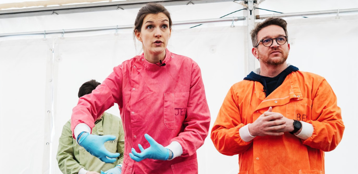 Dr Jess French, wearing a pink surgical suit and blue gloves, standing beside Prof Ben Garrod, who is wearing an orange surgical suit and glasses