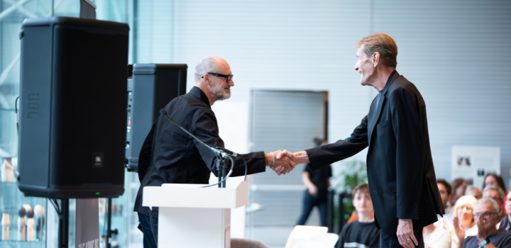 Two men stood on a stage shaking hands
