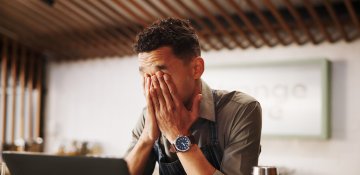 A man sat down with his hands covering his face, looking stressed