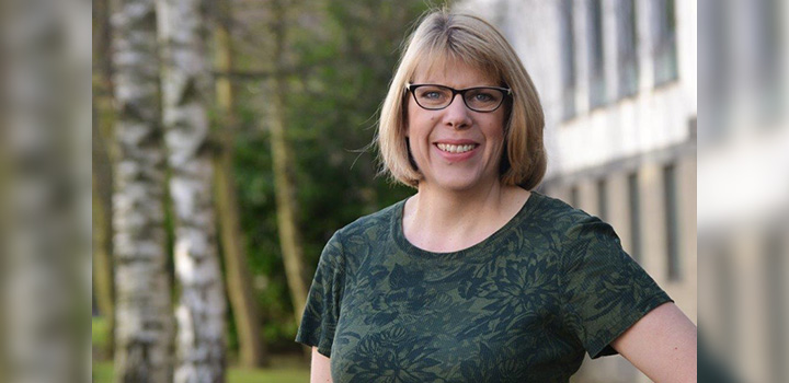 Prof Beth Neil smiling at the camera, with trees in background view