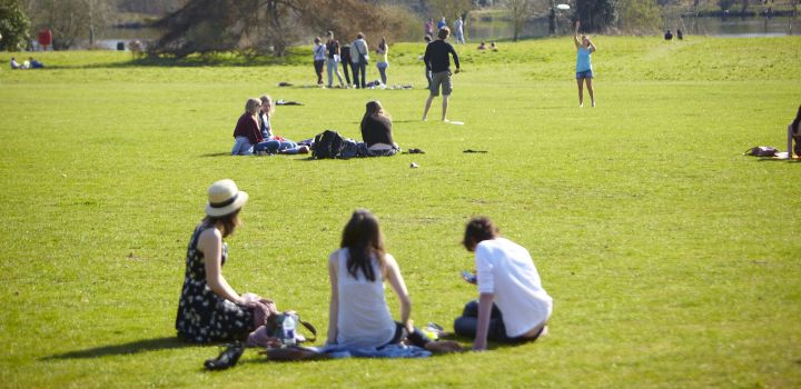 Students relax in the sun on the grass in front of University Broad.