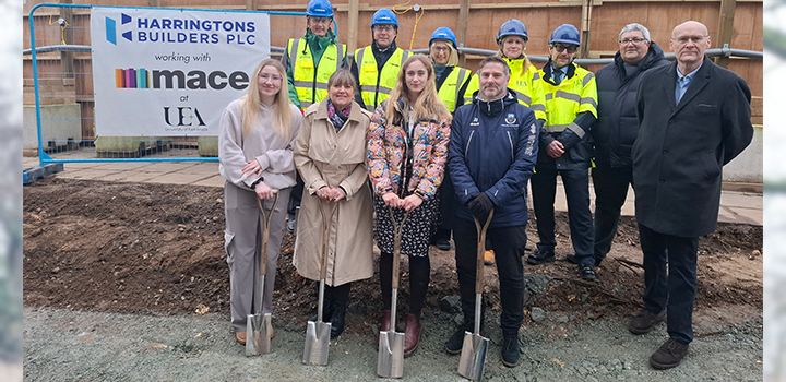 A group of people on a building site with four holding shovels