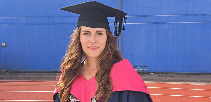 Anna Tanner smiling while wearing a graduation gown and cap
