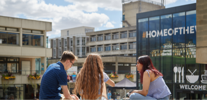 Three people sat down on the floor on the campus of the University of East Anglia