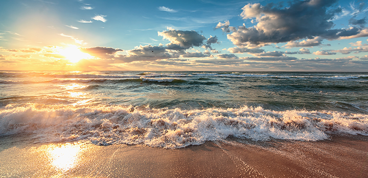 sun and clouds over ocean waves and beach