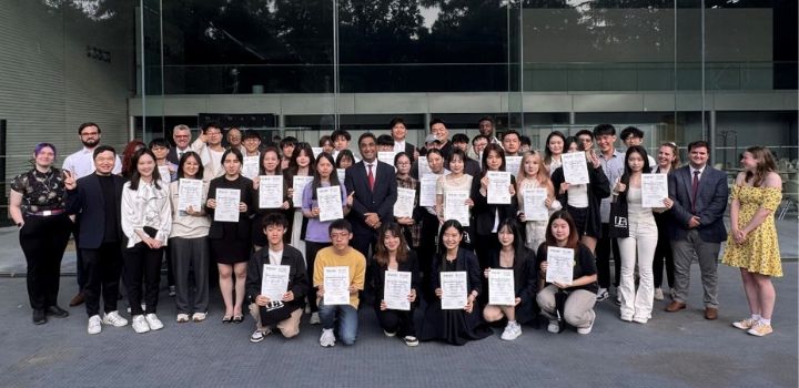 A large group smiling at the camera and holding paper certificates