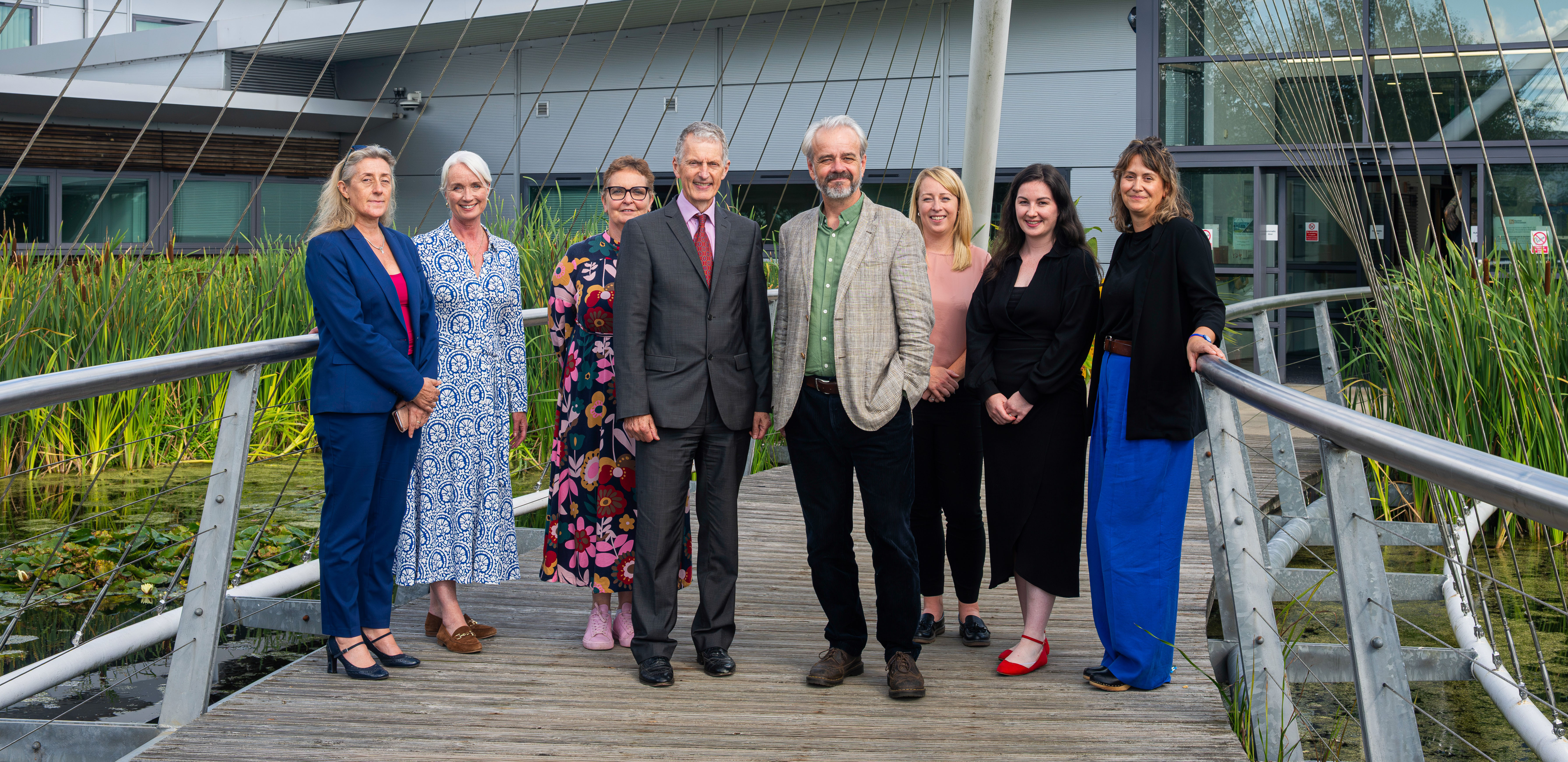 people standing in a row on a bridge outside a building