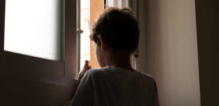 A silhouetted figure of a child looking out of a window