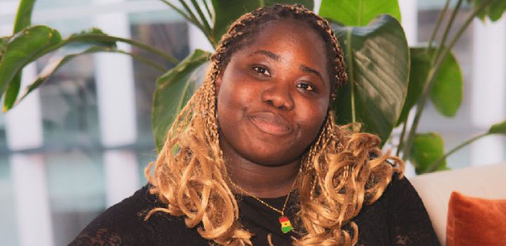 Earlgi Dadzie, a first-year Law student from London, is pictured sitting on a sofa with a plant behind her.
