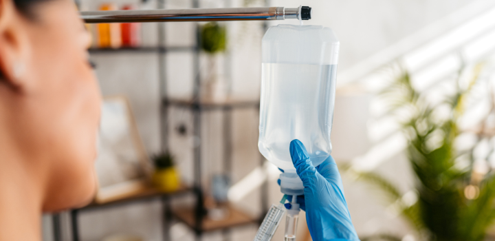 An IV bag being held by a nurse with a syringe in her hand