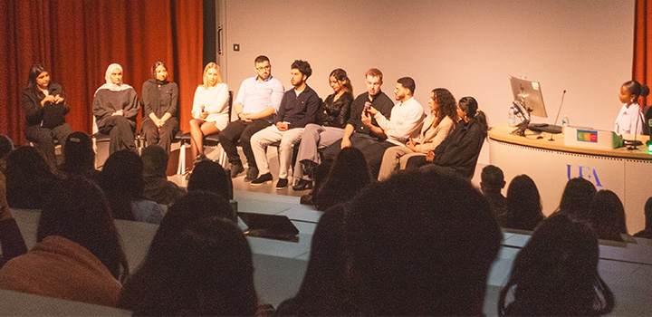 Attendees seated on stage at the ‘Healthcare in a Nutshell’ conference in a lecture theatre, looking out at the audience