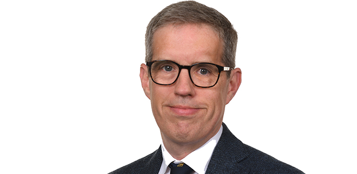 Head shot of Kristian Bowles wearing suit and glasses