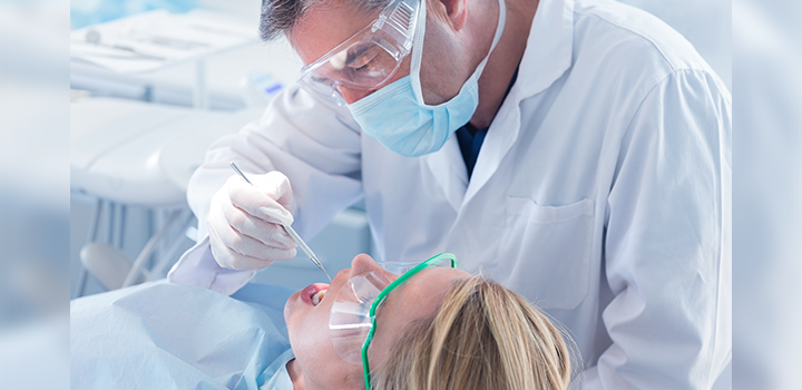 A dentist examining a patient's teeth in a dentistry chair