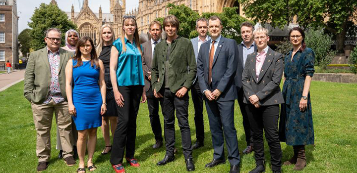 A large group of people standing outside of the Houses of Parliament