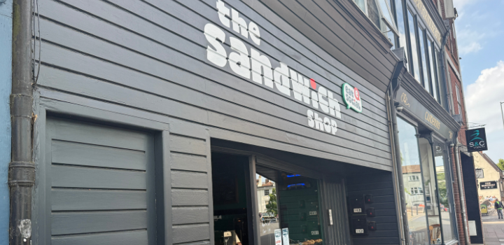 The outside of the Sandwich Shop at 16 Wensum Street, Norwich, the building has black wood and a white sign