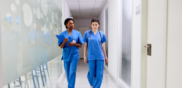 Two people dressed in blue scrubs walking down a corridor