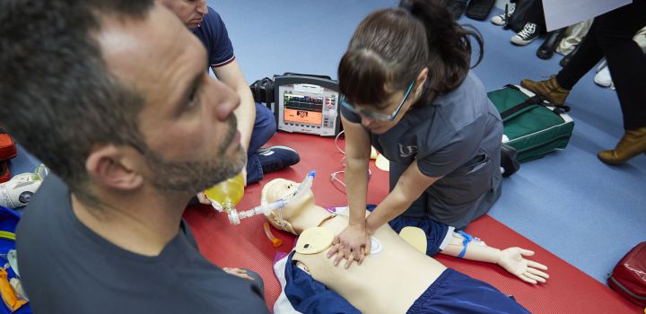 A student performs chest compressions on a medical dummy.