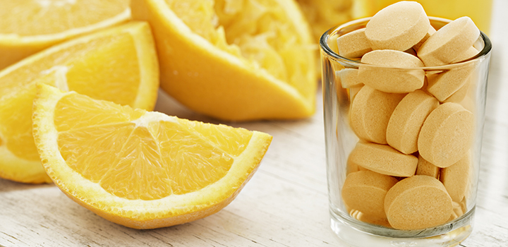 Sliced oranges and a glass of vitamin C tablets