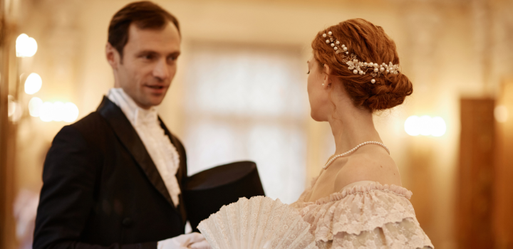 A man and a woman wearing Regency style era clothing, dancing together