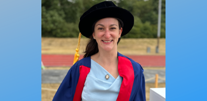 Katherine Howe smiling while wearing a graduation gown and cap