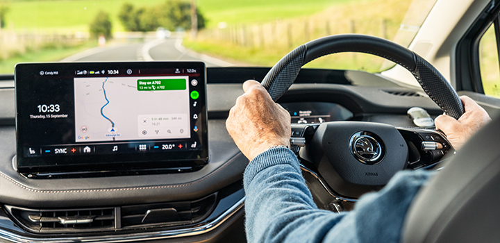 An older driver at the steering wheel of a car, guided by a GPS map.