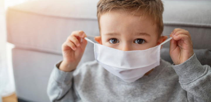 A child putting a clothed face mask over their mouth and nose