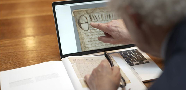 A man points to a laptop screen showing a rare original Magna Carta.