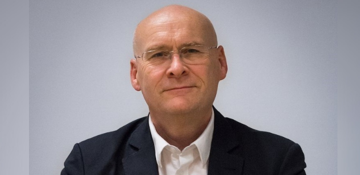 A man stood in front of a grey background