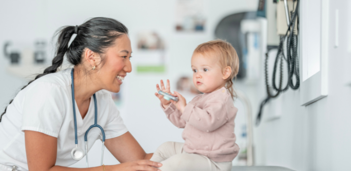 A medical professional smiling at a baby on an observation table