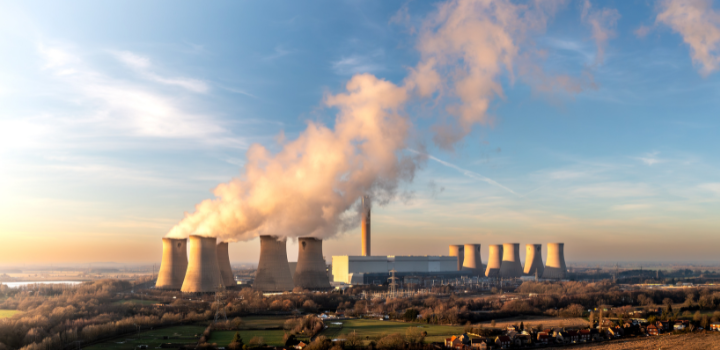 A photo of a power plant, with smoke coming out of the funnels