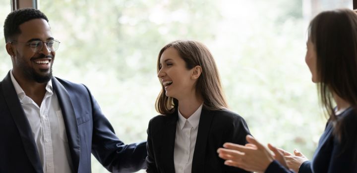 Happy diverse business team applauding coworker success. Employees congratulating promoted colleague, expressing gratitude, recognition, appreciation