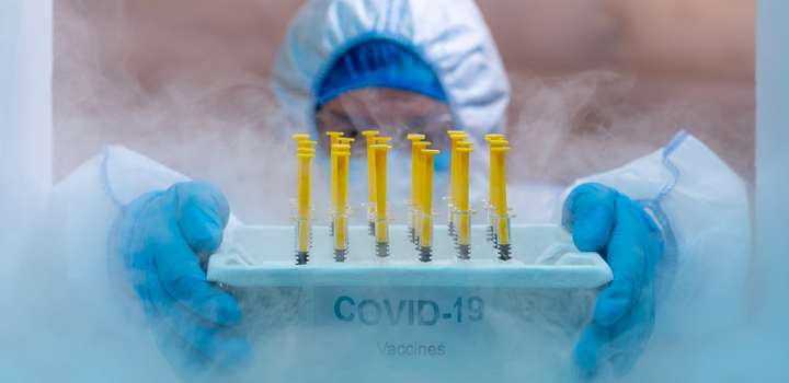 Medical staff take a tray of covid-19 vaccines out of a freezer.