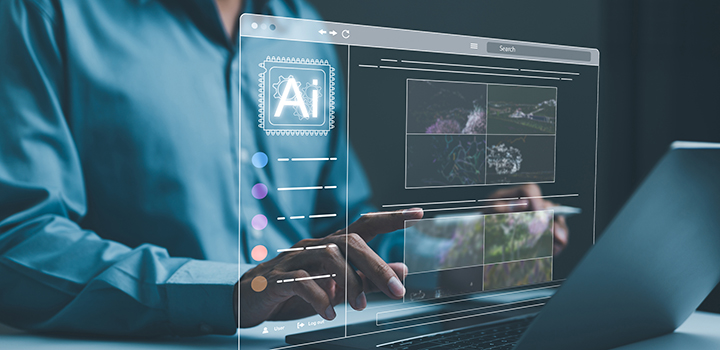 A person in a blue shirt types on a laptop, an overlaid graphic reveals the screen with the letters AI shown prominently