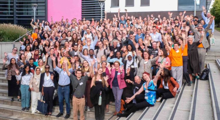 Group photo on the steps outside the New Science Building at UEA of cheering delegates attending a conference marking the Tyndall Centre's 25th anniversary