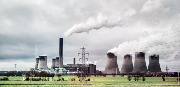 A photo of a power plant, with smoke coming out of the funnels