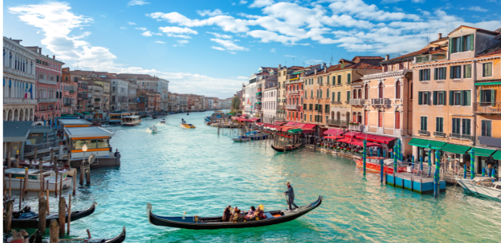 A photo of a canal in Venice, with colourful buildings along the side and a gondola on the water