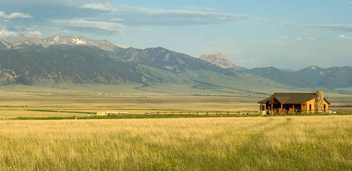 A ranch house on a grassland with hills behind.