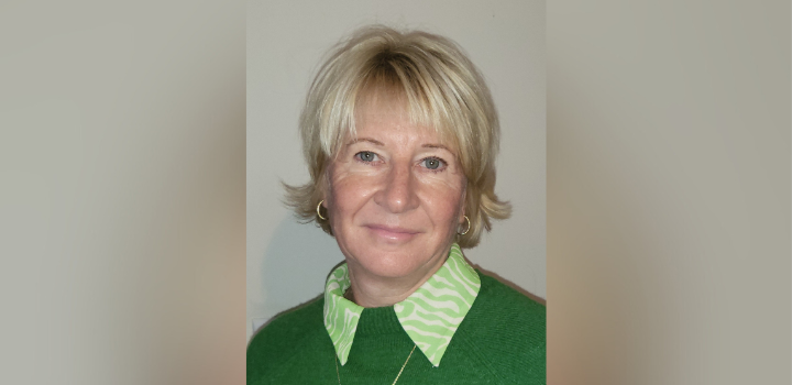 Prof Nicola Spalding smiling at the camera, wearing a green jumper with a green striped collar