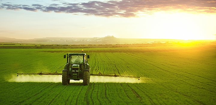 A tractor spraying fertilizer on a field.