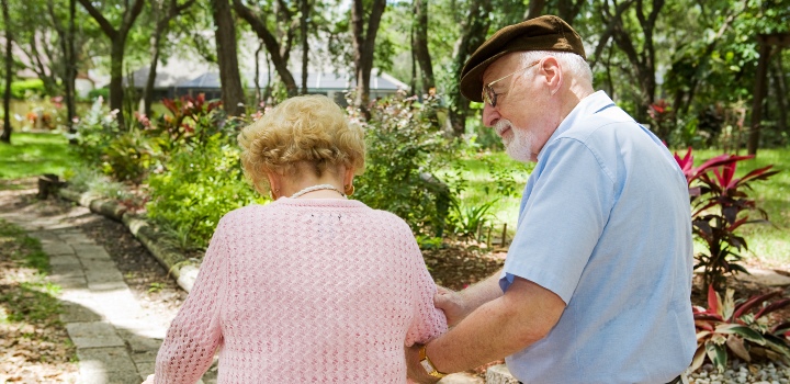 Senior carer walking outside with his partner