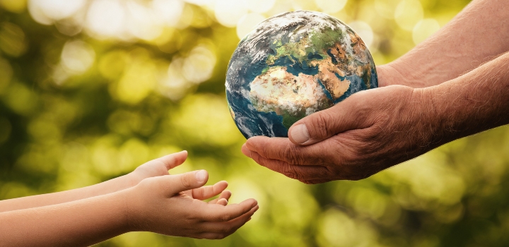 Senior hands giving small planet earth model to a child