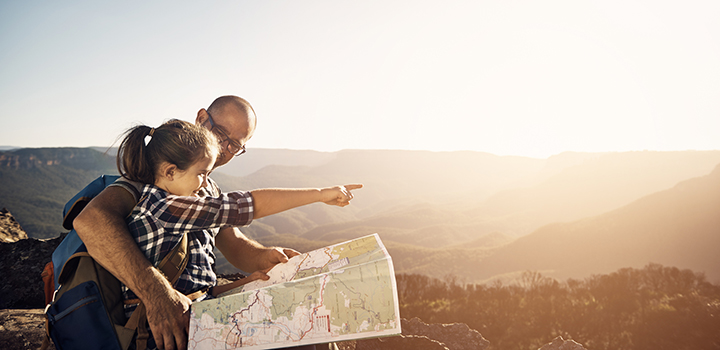 A dad helping his young daughter read a map.