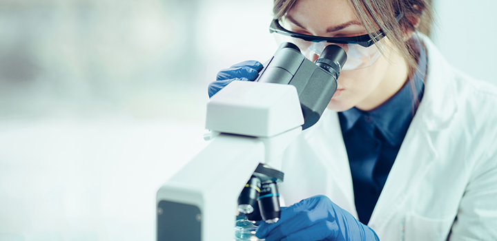 A female researcher looks down a microscope