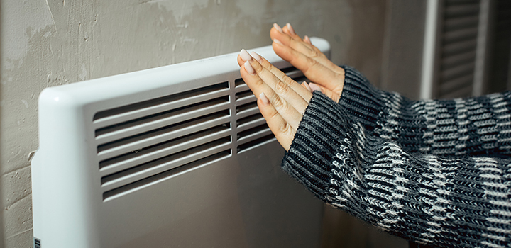 A pair of hands are warmed next to a radiator