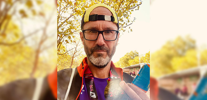 Jason Corner wearing a hat and black rimmed glasses